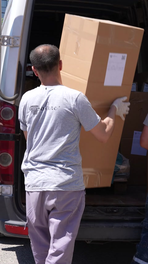 A boxed custom element is loaded into a delivery van.