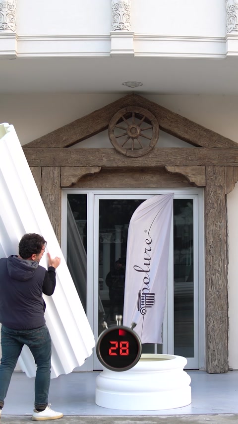 A worker positions a tall decorative element beside an entrance column.