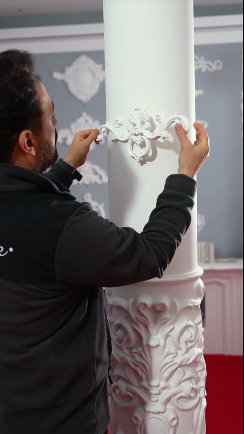 A craftsman aligns a flexible decorative appliqué on a round column.