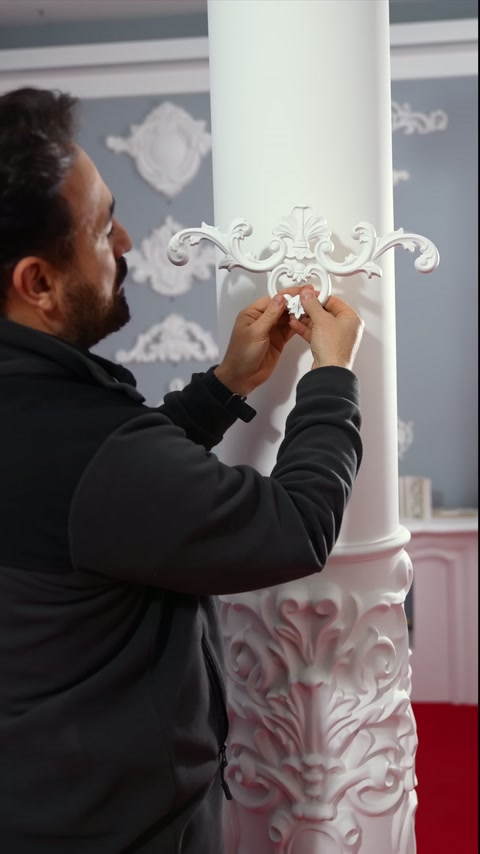 A polyurethane motif is adapted by two hands to the cylindrical column's curve.