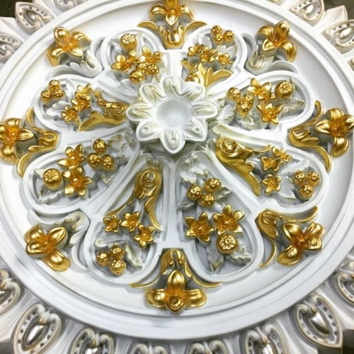 Rosone in poliuretano con dettagli dorati per decorazione di villa classica <h2>Rosone classico in poliuretano dorato</h2><p>Il <strong>rosone</strong> in poliuretano con dettagli dorati rappresenta un elemento decorativo di pregio, ideale per soffitti di ampie sale o saloni di ville classiche. La superficie bianca funge da base luminosa, mentre le applicazioni in foglia d’oro creano giochi di luce raffinati.</p><p>I rilievi floreali sono composti da piccoli <strong>fiori</strong>, bacche e stilizzazioni vegetali, organizzati in modo radiale attorno al centro del rosone. Questa disposizione dona armonia e continuità visiva, unendo l’estetica alla simmetria architettonica tipica dello <strong>stile classico</strong>.</p><p>L’utilizzo del <strong>poliuretano</strong> garantisce non solo leggerezza ma anche durabilità, rendendo l’oggetto facile da installare senza rinunciare a un impatto decorativo importante. La lavorazione in rilievo conferisce un effetto tridimensionale che arricchisce gli ambienti interni.</p><p>Storicamente, i rosoni e le decorazioni centrali a soffitto erano diffusi nelle architetture barocche e neoclassiche, spesso arricchiti con oro per simboleggiare lusso e prestigio. Questo design ne riprende lo spirito, offrendo una reinterpretazione moderna.</p><ul><li>Motivi floreali dorati in rilievo</li><li>Base in poliuretano bianco</li><li>Stile classico e barocco</li><li>Decorazione simmetrica a tema vegetale</li></ul><p>Perfetto per chi cerca un dettaglio di lusso, il rosone diventa un punto focale che cattura lo sguardo e valorizza qualsiasi ambiente d'ispirazione classica.</p>

<p>Il <strong>rosone</strong> in poliuretano con dettagli dorati unisce eleganza e funzionalità. La forma circolare con motivi floreali porta armonia agli ambienti. I rilievi dorati illuminano la base bianca con giochi di luce raffinati. Ogni <strong>fiore</strong> scolpito aggiunge profondità e ricchezza visiva. La disposizione radiale crea un equilibrio perfetto. Le bacche e i dettagli botanici arricchiscono la composizione. Lo <strong>stile classico</strong> domina nella simmetria e nelle forme. Il materiale in poliuretano assicura leggerezza e resistenza. L’installazione è semplice ma il risultato è sontuoso. Perfetto per soffitti di ville eleganti o saloni importanti. Richiama l’eredità barocca senza perdere modernità. I riflessi dorati sottolineano l’atmosfera di lusso. Il <strong>design</strong> raffinato valorizza gli spazi ampi. Ogni dettaglio racconta attenzione artigianale. Questo oggetto è un complemento ideale per creare raffinate decorazioni interne.</p>